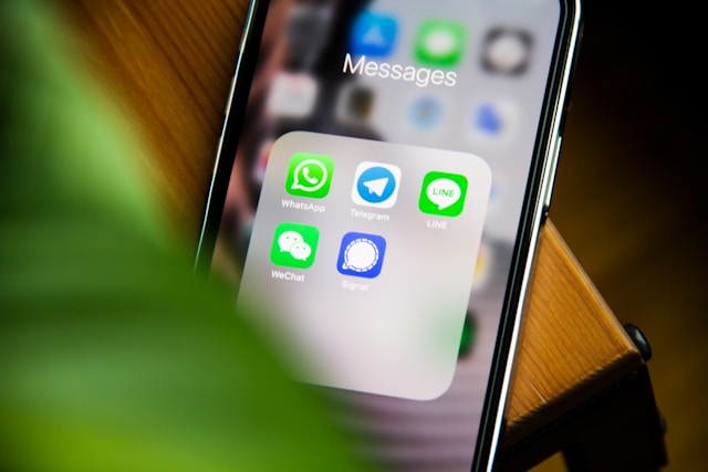 Close-up of a smartphone screen displaying a "Messages" folder containing icons for WhatsApp, Telegram, LINE, WeChat, and Signal.