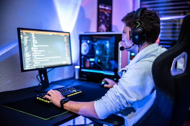A man with a headset sitting at a desk using Discord on a desktop computer with a glowing PC tower